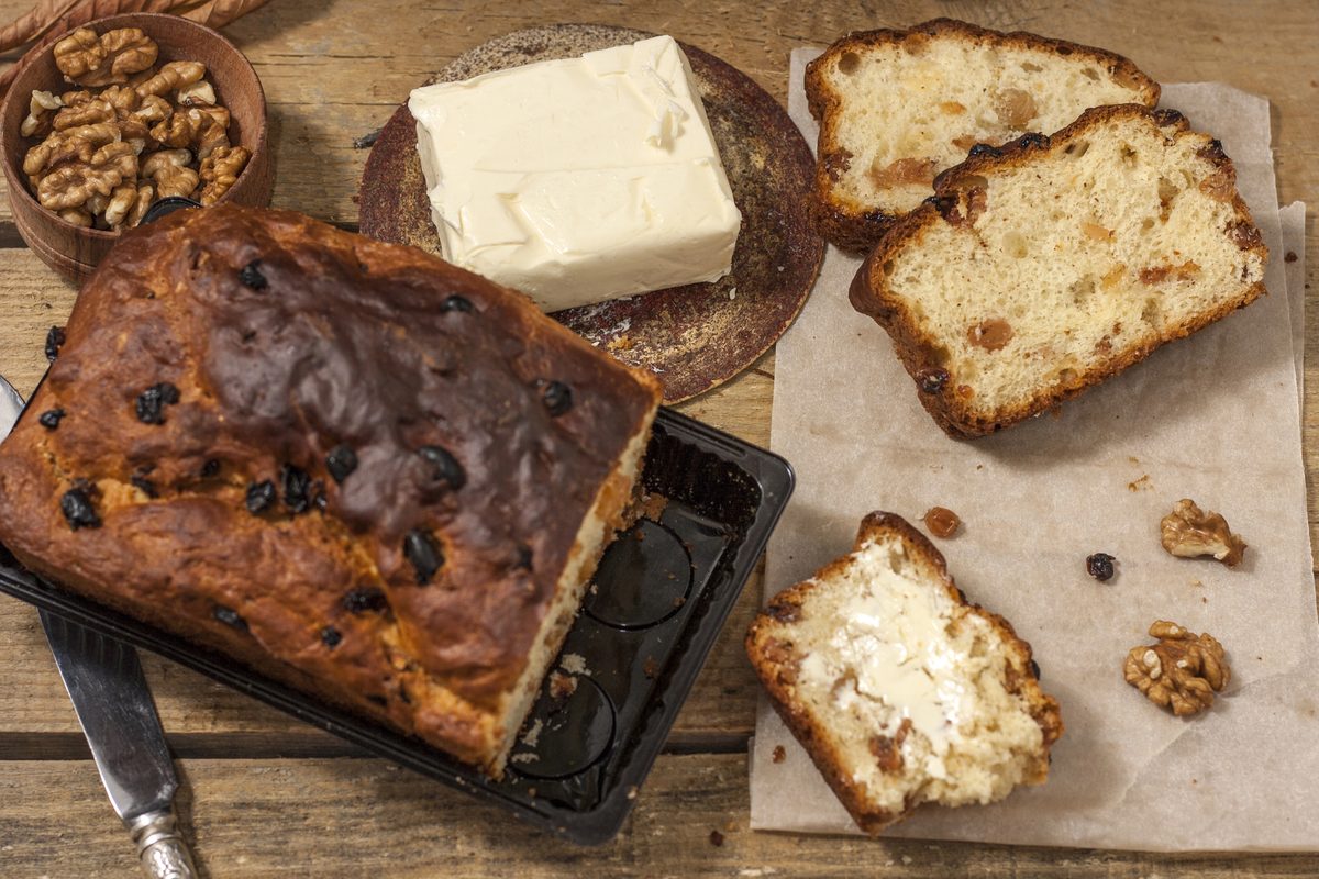 Barmbrack, Irish fruit bread with raisins, sliced on a board with butter and walnuts