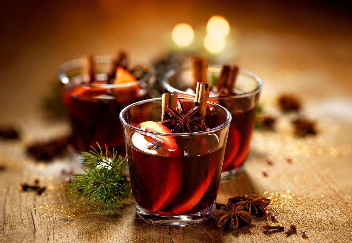 Glasses of vin brulé mulled wine with orange and spices by candlelight