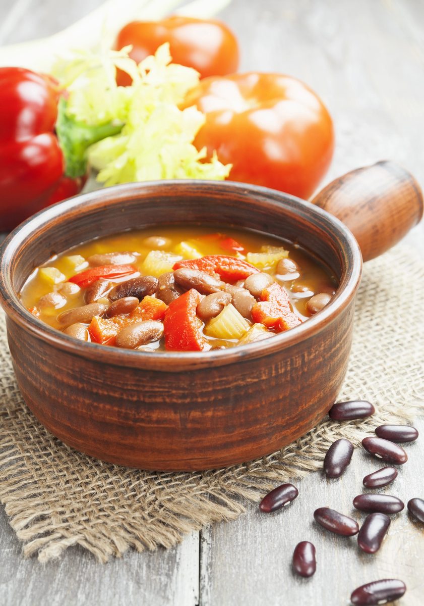 Meatless bean soup with tomato and peppers in a clay bowl