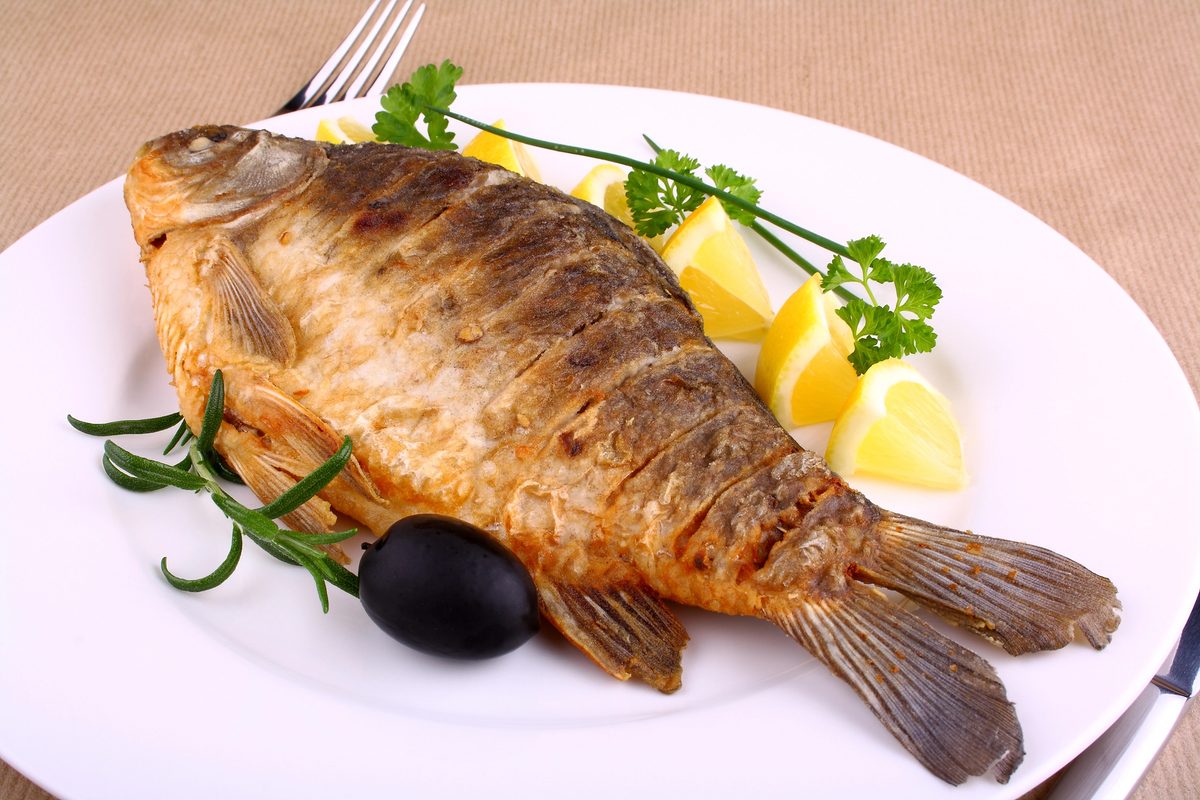 Fried carp with lemon on a white plate