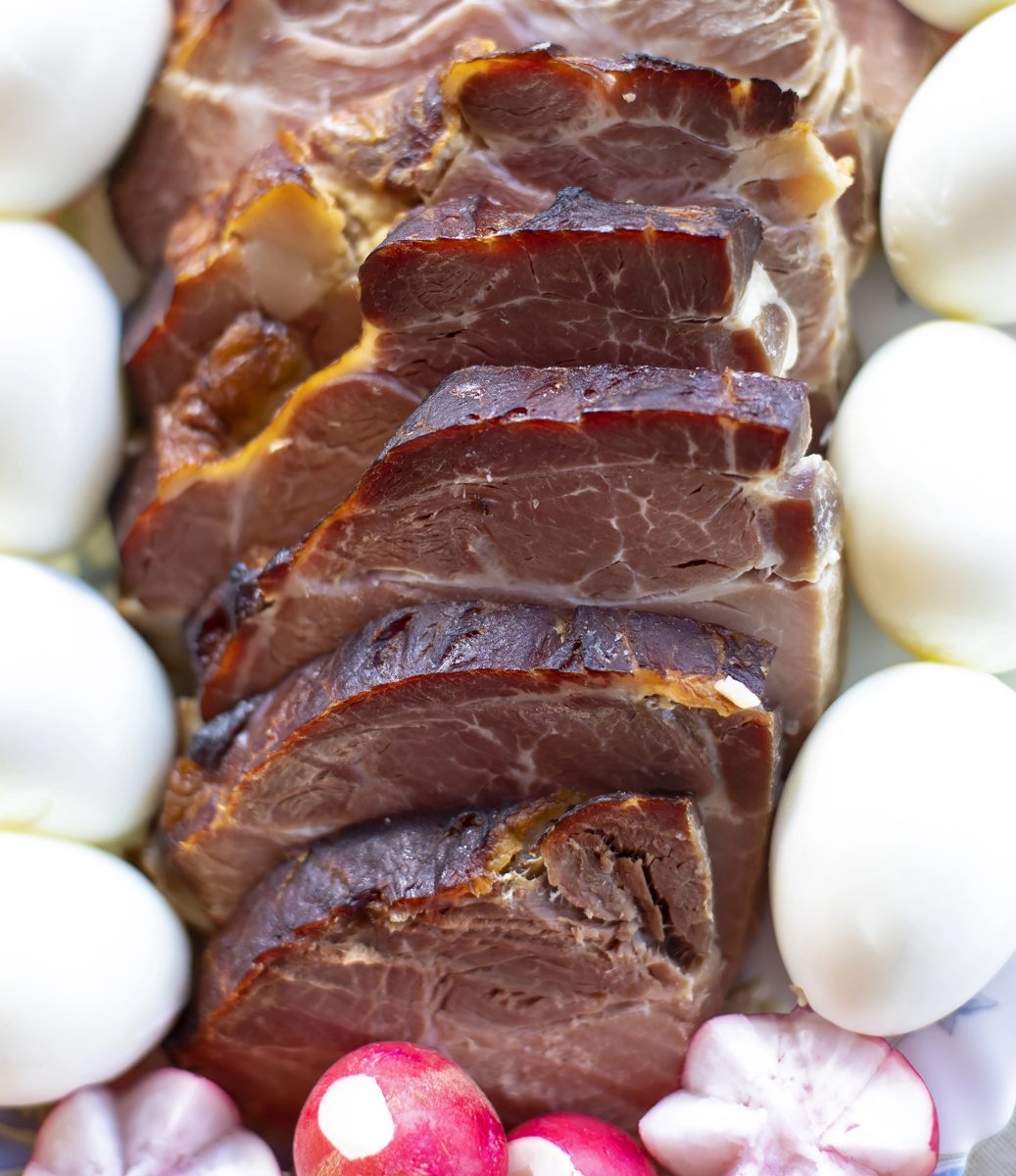 Sliced Easter ham with boiled eggs and radishes