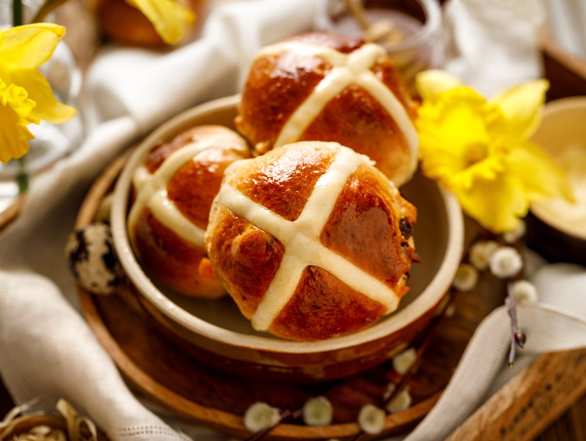 Hot cross buns in a ceramic bowl with daffodils