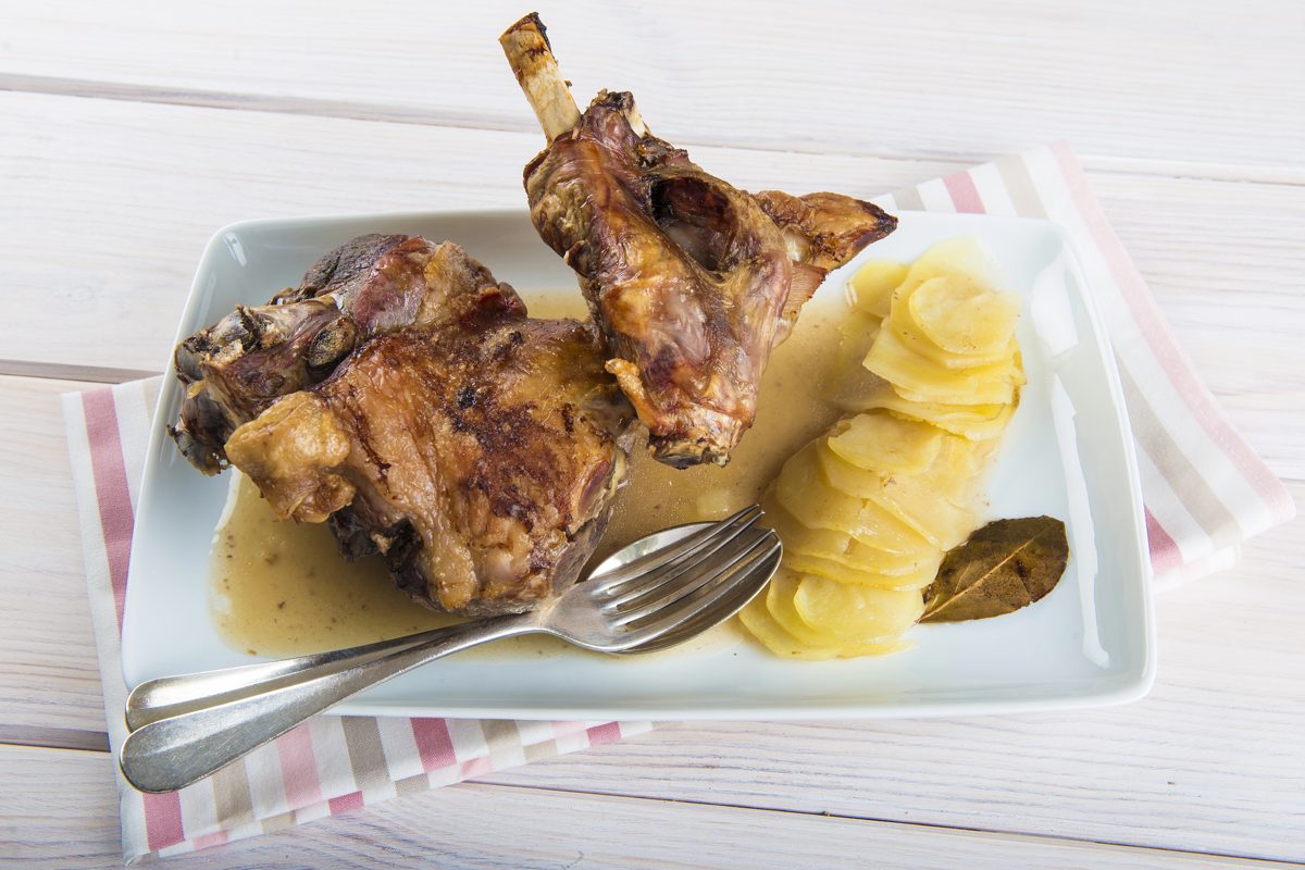Roast leg of lamb with potatoes on a white plate