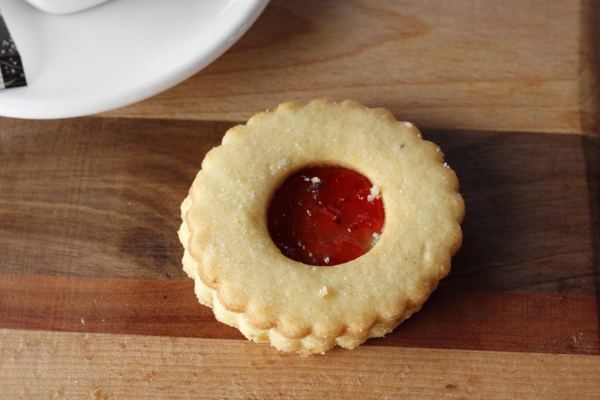 Linzer cookie with a red jam center on a wooden board