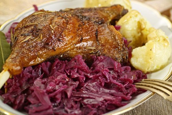 Roast goose leg with braised red cabbage and potato dumplings on a plate