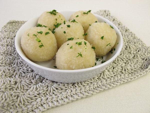 Kartoffelklöße, round German potato dumplings sprinkled with herbs, in a white bowl