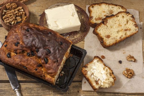 Barmbrack, Irish fruit bread with raisins, sliced on a board with butter and walnuts