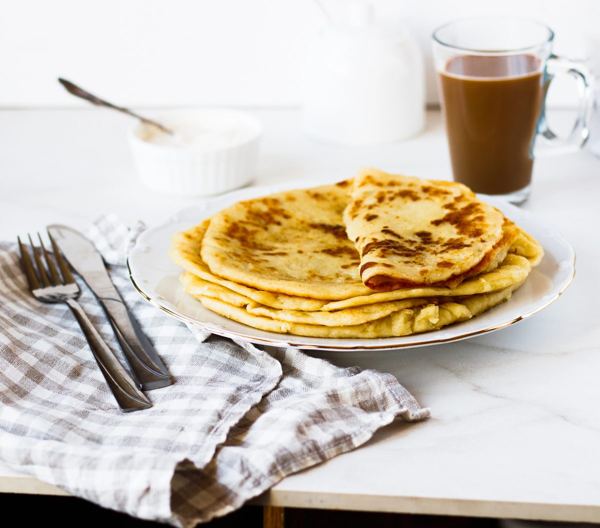 Folded Norwegian lefse potato flatbreads on a plate, with a mug of coffee