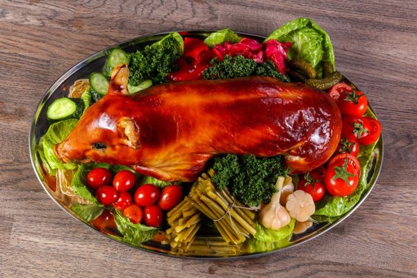Roast whole suckling pig on a platter with vegetables