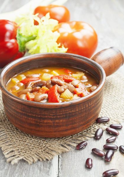 Meatless bean soup with tomato and peppers in a clay bowl
