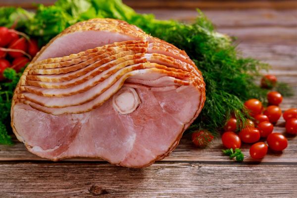 Glazed Christmas ham, sliced, with fresh herbs and cherry tomatoes