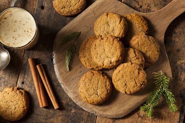 Round ginger snap cookies on a wooden board with cinnamon sticks