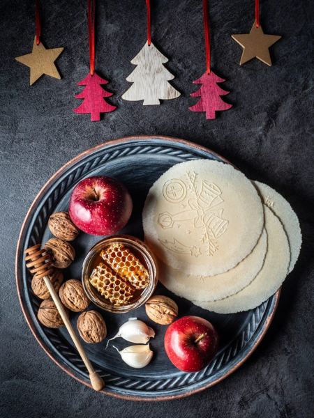 Christmas Eve table setting with thin wafers, honey, apples, walnuts and garlic