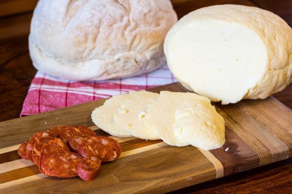 Round Easter egg cheese (hrudka) sliced on a board with sausage