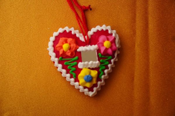 Red licitar heart decorated with white icing and a small mirror