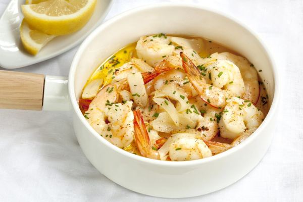 Prawns in garlic butter in a white dish with lemon